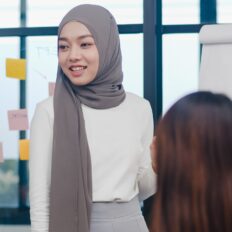 Asia businessmen and businesswomen meeting brainstorming ideas conducting business presentation project colleagues working together plan success strategy enjoy teamwork in small modern office.